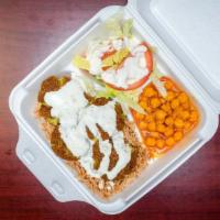 Falafel Over Rice  · Falafel served over brown rice with a side of chickpeas and salad and white sauce on top