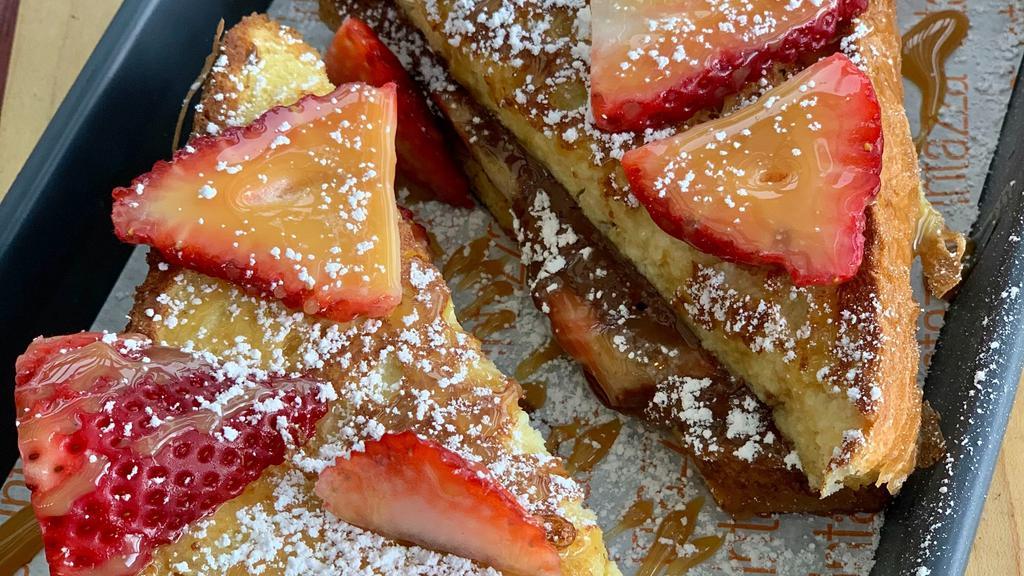 Strawberry Nutella French Toast Sando · Two slices of thick-cut Texas toast filled with Nutella and strawberries and garnished with caramel and powdered sugar.