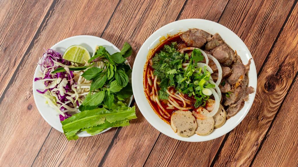 (Sp8) Bun Bo Hue / Spicy Beef Noodle · Spicy lemongrass, meatloaf, pork leg & beef broth with round rice noodle and slices of fresh cooked beef & pork blood.