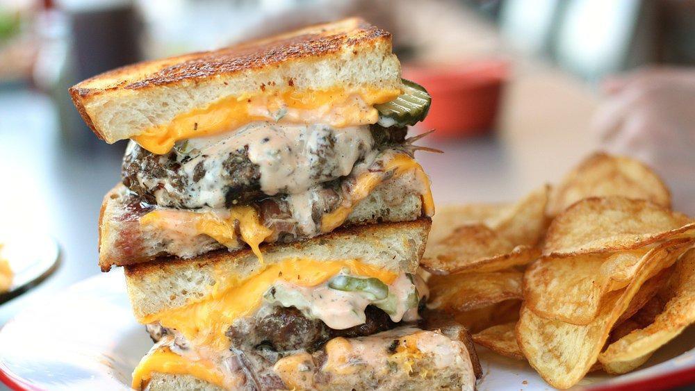 All-American Beach Melt · Over one lb of handmade char-grilled patties and melted all-American cheese on toasted sourdough, smothered with grilled onions, Mama's special sauce and pickle.