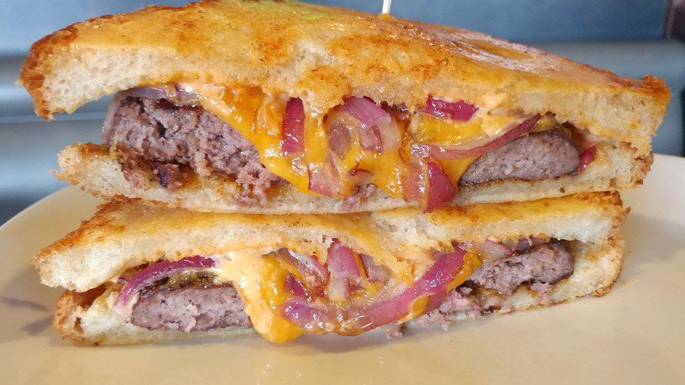 Parmesan Patty Melt · Topped with cheddar, sautéed red onions, and thousand island dressing. Served on sourdough Parmesan toast.