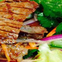 Num Tok Salad · Grilled marinated slices of beef with roasted rice in spicy fresh lime dressing on a lettuce...