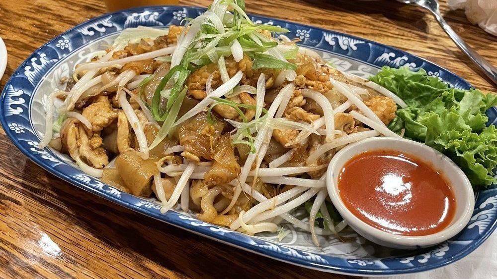 Kua Gai · Spicy, Gluten-free.Sautéed flat noodles with eggs, garlic, preserved turnips, bean sprouts served on bed of lettuce with sriracha sauce. ( chicken and calamari )