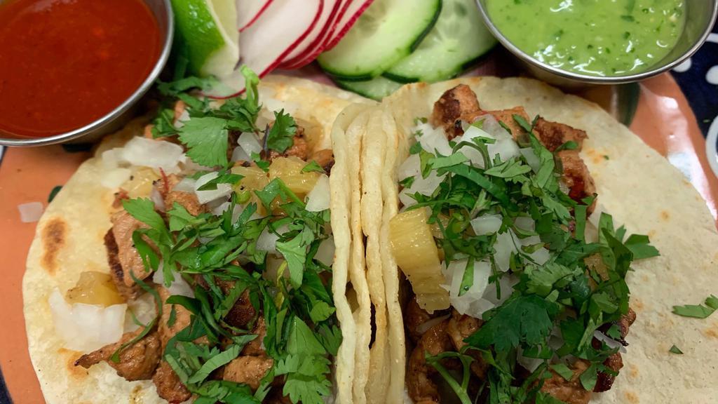 (2) Tacos - Al Pastor · (2) TACOS W/ ADOBO, ROASTED PORK SHOULDER & TOPPED OFF W/ GRILLED PINEAPPLE + TOPPINGS OF YOUR CHOICE. 
AVAILABLE TOPPINGS: ONIONS, CILANTRO, SALSAS, LIMES, AVOCADO, OAXACA CHEESE & MORE.