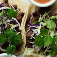 Grilled Beef Tenderloin Tacos · 2 Corn tortilla tacos topped with sauteed onions, fresh cilantro & served with cilantro-ging...