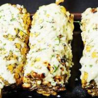 Corn · Sweet corn marinated, grilled, and drizzled with our house garlic sauce, green oil, and spri...