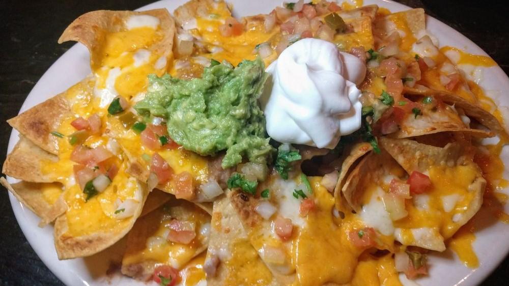 Nachos · Corn chips topped with refried beans, melted cheese, in a light tomato-tomatillo sauce, pico de gallo, guacamole & sour cream.