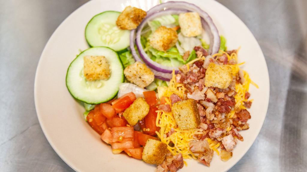 Deluxe Salad · Crisp lettuce mixed with shredded carrots & cabbage topped with cheddar cheese, bacon bits, croûtons, red onions, tomato and cucumber & your choice of dressing.