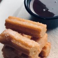 Churros. · Fried churros tossed with cinnamon sugar and served with a side of hazelnut-chocolate dippin...