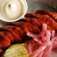 Our Smoked Sausage · Smoked, House Recipe Sausage Link Served with Pickles, Pickled Red Onions, and Smoked Mustar...