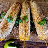 Street-Corn Elotes · whole corn on a stick, smothered in special creamy sauce, coated with cotija cheese and chil...