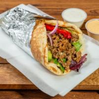 Mediterranean Chicken Gyro Wrap · Sliced marinated chicken in a bread with chopped salad and topped with homemade sauces.