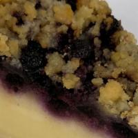 Blueberry Cheesecake · A creamy lemon cheesecake topped with blueberries and brown sugar crumbs, sits on a cookie b...