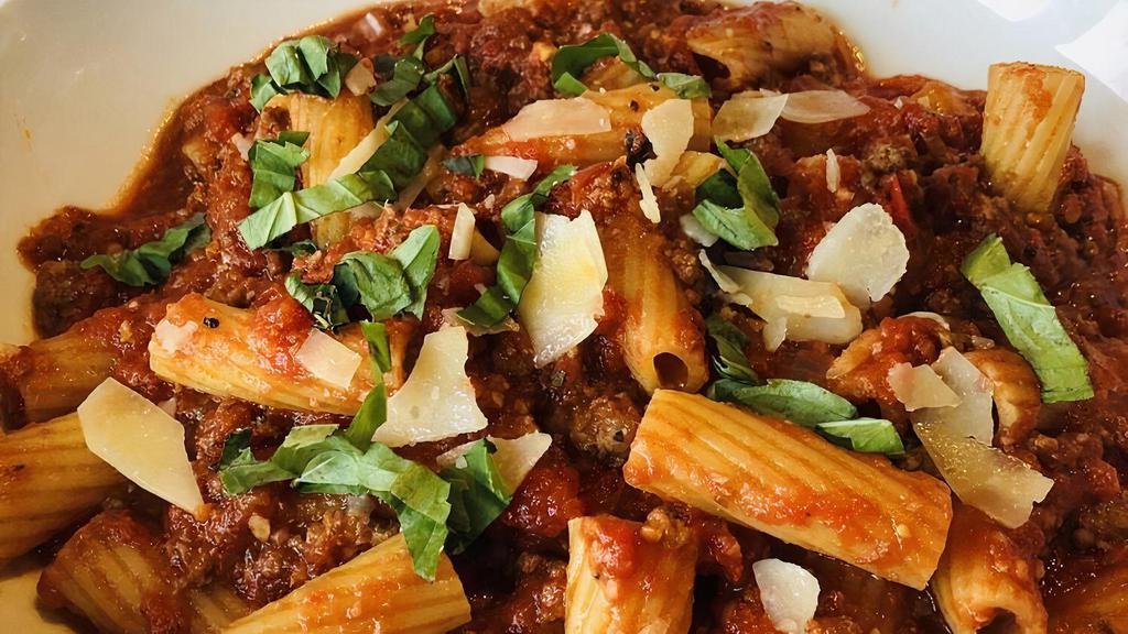 Rigatoni Bolognese · Rigatoni pasta tossed with a mix of veal, pork and beef simmered in a rich tomato sauce, garnished with fresh basil and cheese.