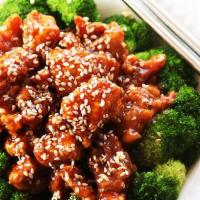 Sesame Chicken · Chunk of chicken sautéed in special brown sauce with sesame seeds on top and broccoli on side.