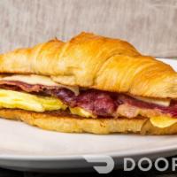 Bacon, Egg And Cheese Croissant Sandwich · A scrambled egg base, halal beef bacon, and melted cheddar cheese all sandwiched between a l...