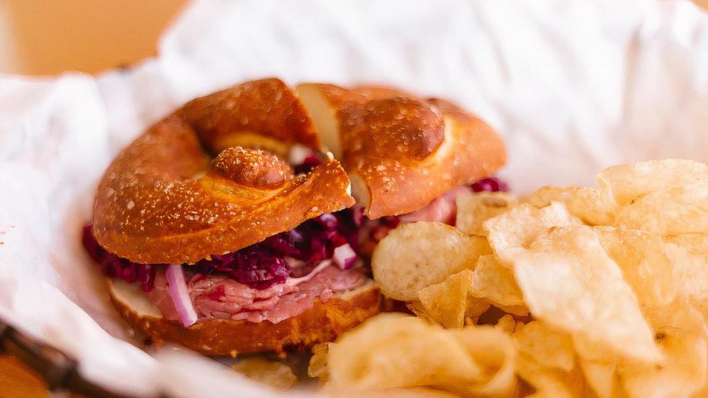Roast Beef Pretzel Sandwich · Sliced roast beef, shaved red onion, red cabbage slaw and garlic aioli served on a salted pretzel with kettle chips.