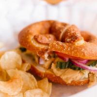 Gf Hummus · Hummus, tomato, lettuce, onion and cucumber on a salted pretzel bun with kettle chips.