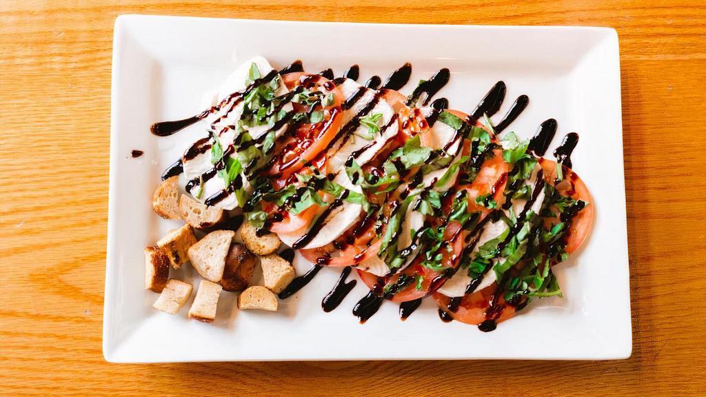 Caprese Salad · Fresh sliced mozzarella, sliced tomatoes, basil leaves, and pretzel croutons drizzled with aged balsamic vinegar.