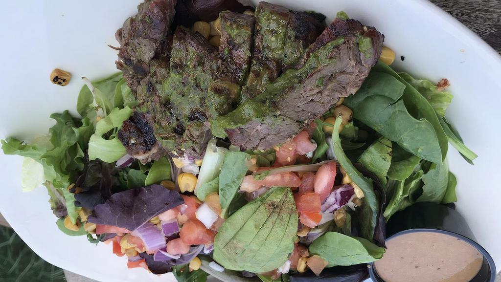 South Texas Steak Salad · Made in Texas. Mixed greens, tomatoes, black bean corn relish, avocado, creamy cilantro, grilled steak, salsa verde.