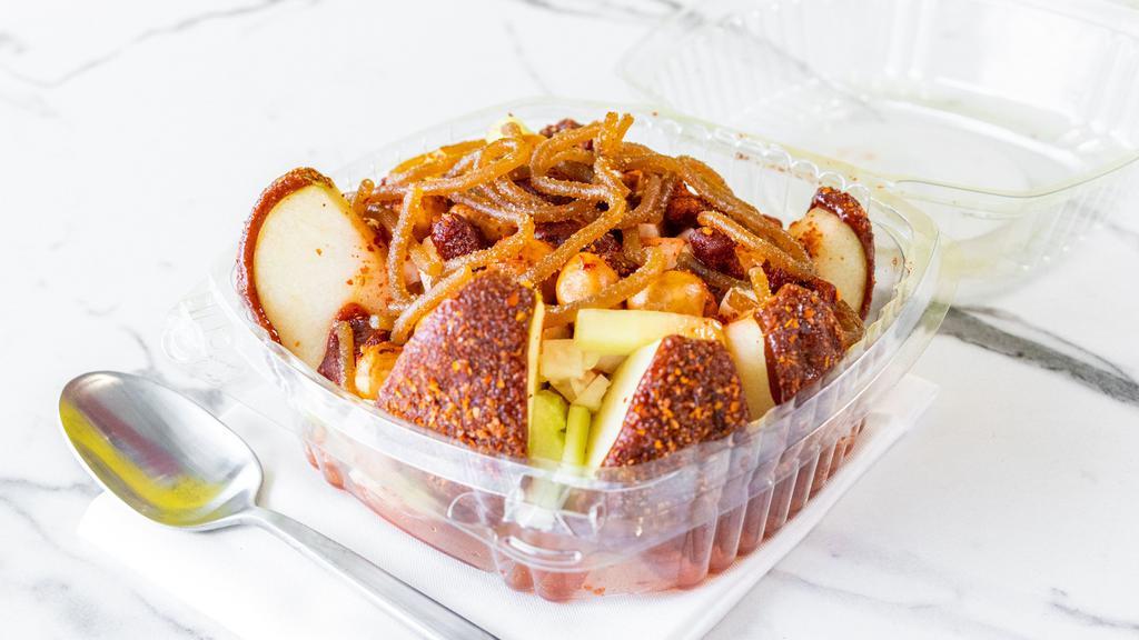 Prepared Crazy Apple · Chamoy covered apple cut in sliced covered in chamoy and Tajin, topped with jicama and cucumber bits, Japanese Style Peanuts, and Chaka Chaka candies