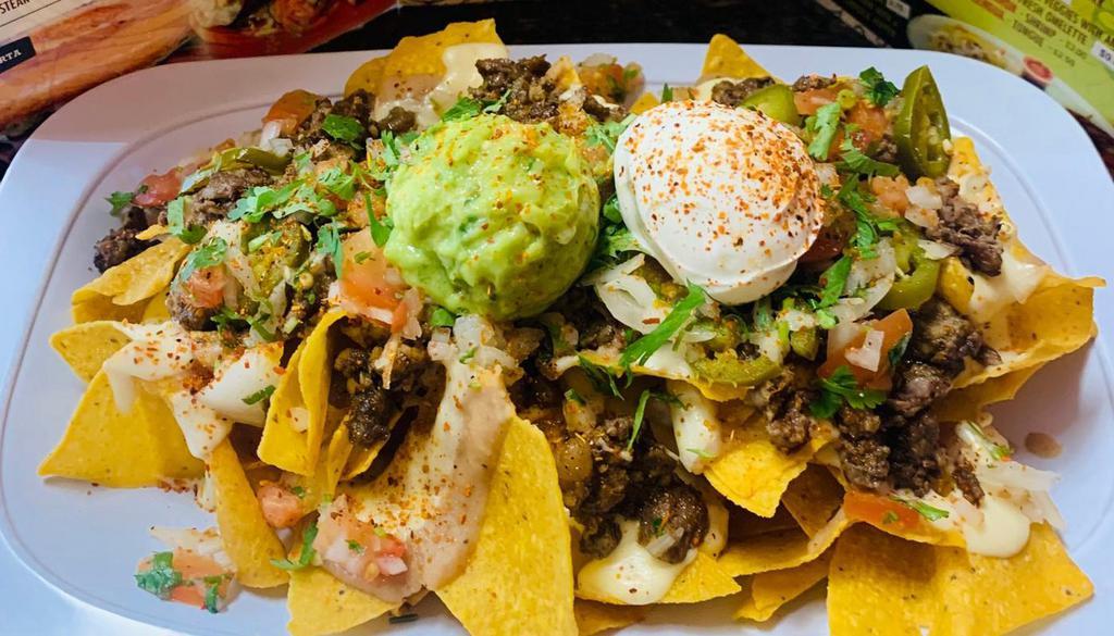 Asada/Nachos · Mega nachos, they come with Newyork Steak, re-fried pinto beans, melted cheese, pico de gallo, guacamole, pickled jalapenos, salsa verde, and a touch of cilantro.