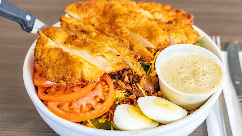 Chicken Cobb · Breaded chicken cutlet, shredded cheddar cheese, bacon, tomatoes, and hard boiled eggs served over romaine lettuce.