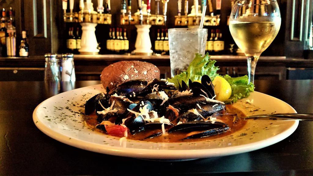 Mussels Malone · Succulent mussels sautéed with garlic, onions, tomatoes, thyme and white wine. Sprinkled with parmesan cheese and served with lemon and a rustic roll.