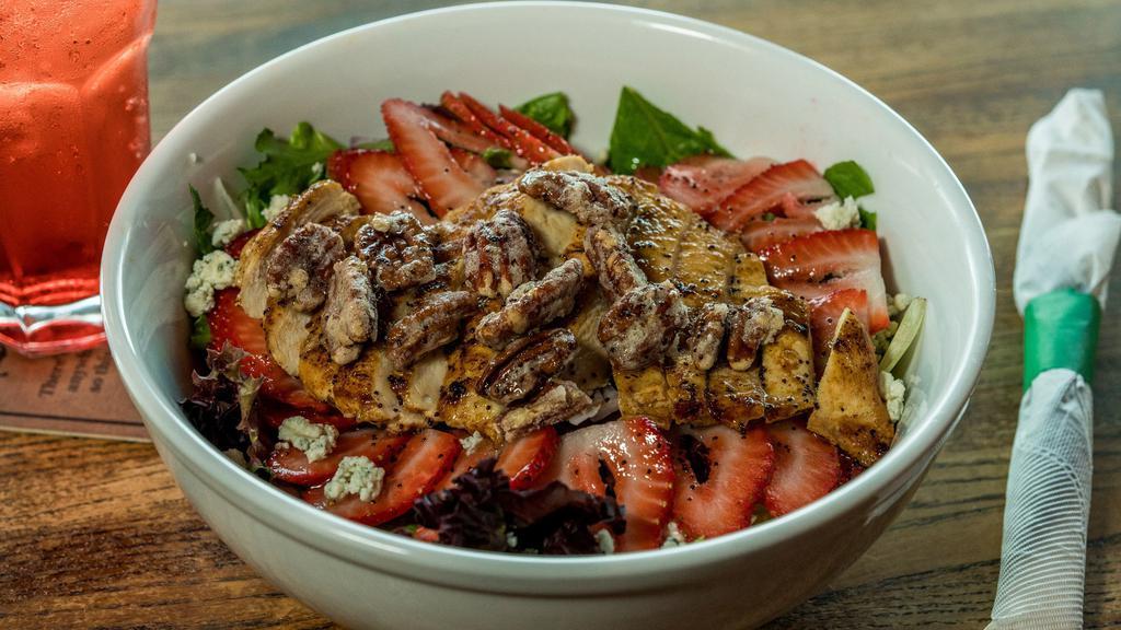 Strawberry Pecan Salad · Crisp romaine lettuce and spring greens topped with fresh strawberries, candied pecans, bleu cheese crumbles, diced red onion and a juicy 7 oz. chicken breast. Drizzled with poppy seed dressing.