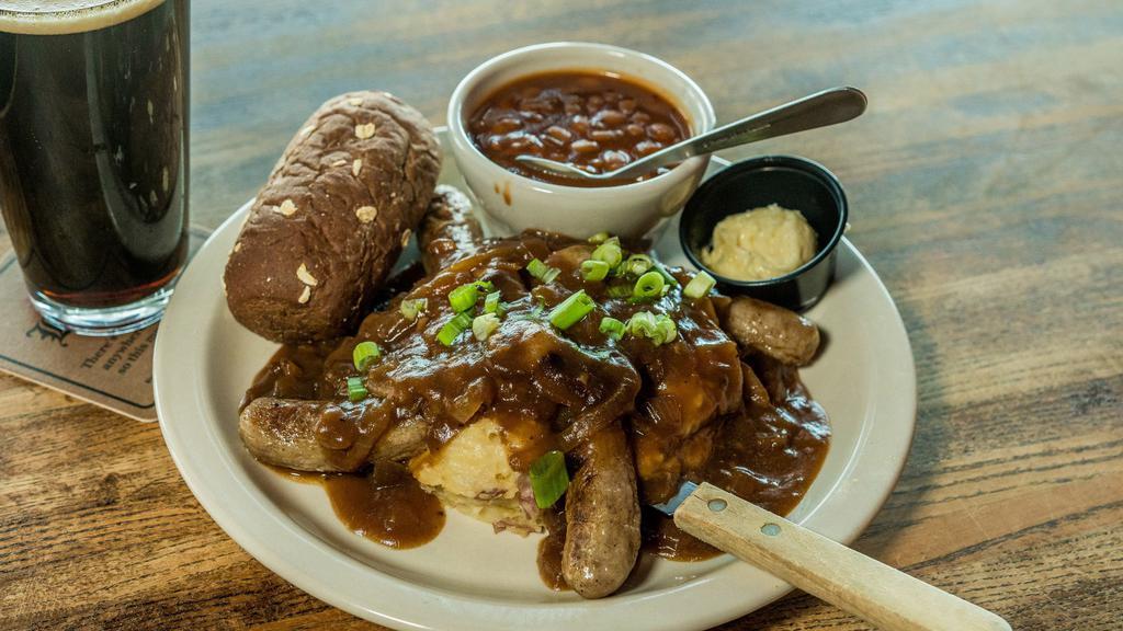 Bangers & Mash · Champ potatoes topped with four authentic Irish sausages, sautéed onions, rosemary onion gravy and green onion. Accompanied by baked beans, a rustic roll and honey butter.