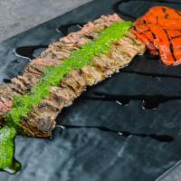 Churrasco Con Chimichurri · Juicy, grilled skirt steak topped with chimichurri sauce, served with roasted red peppers