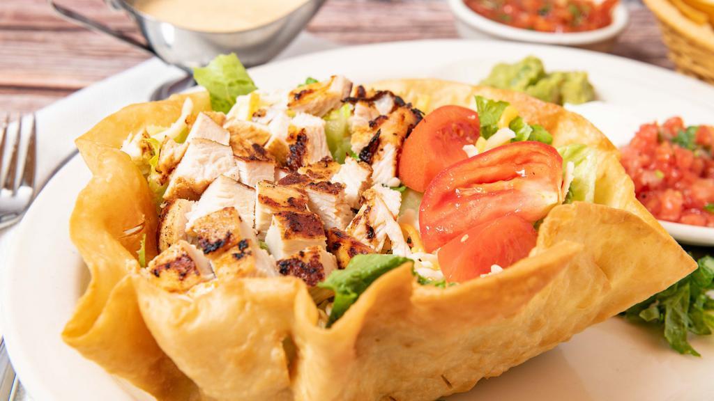 Tostada Chicken Salad · Crispy flour tortilla shell filled with romaine lettuce, tomatoes, shredded cheese, guacamole, and sour cream.