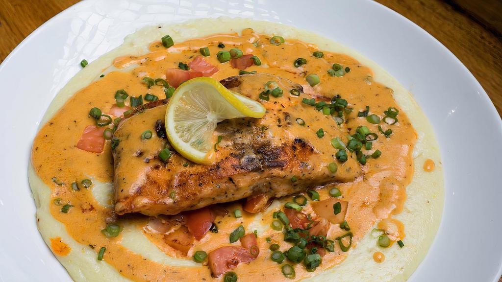 Blackened Salmon & Grits · Fresh blackened salmon served over cheesy grits with our signature cajun cream sauce and tomatoes.