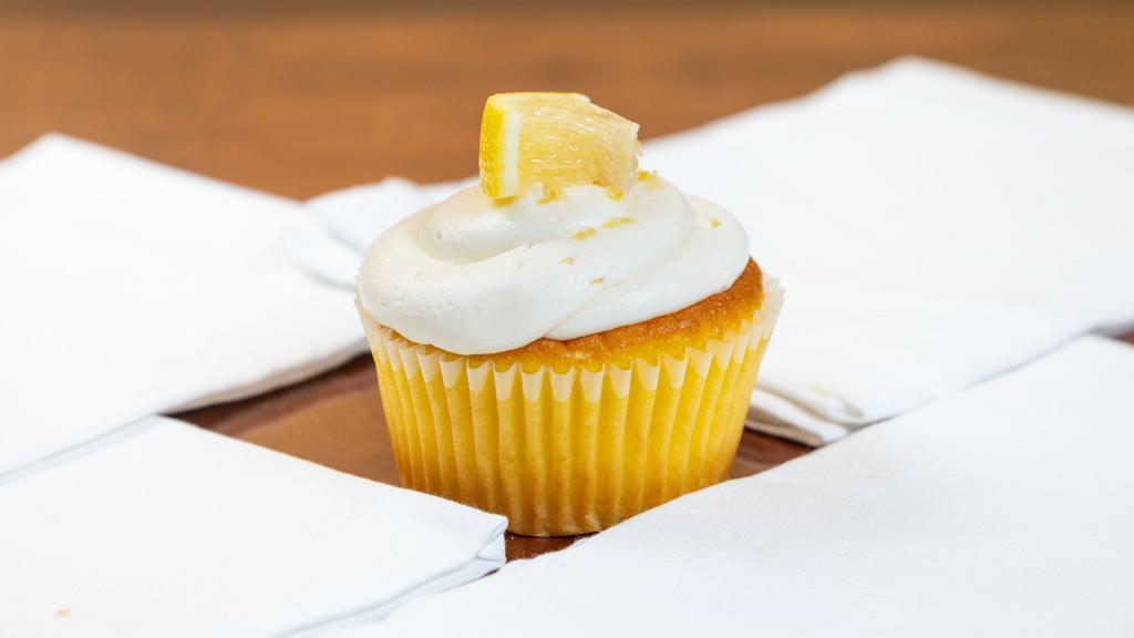 Lemon Delight · A fresh lemon cupcake topped with lemon zest cream cheese frosting and garnished with a lemon wedge.