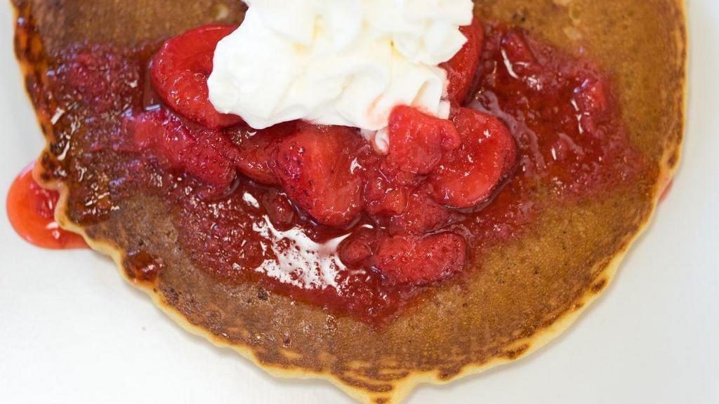 Strawberry Pancakes · Stack of three golden brown pancakes topped with strawberries.