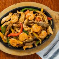 Fajitas Texanas · Tender-sliced steak, chicken and shrimp grilled with green, yellow and red peppers, onions a...