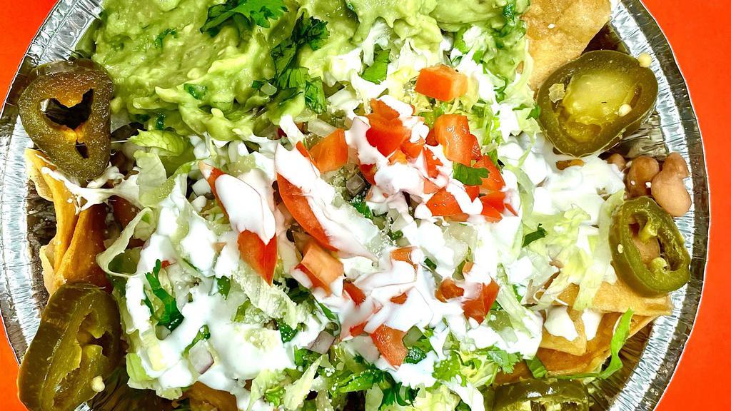 Nachos · Tortilla chips con frijoles, quesillo, lechuga, guacamole, jalapeños y crema.