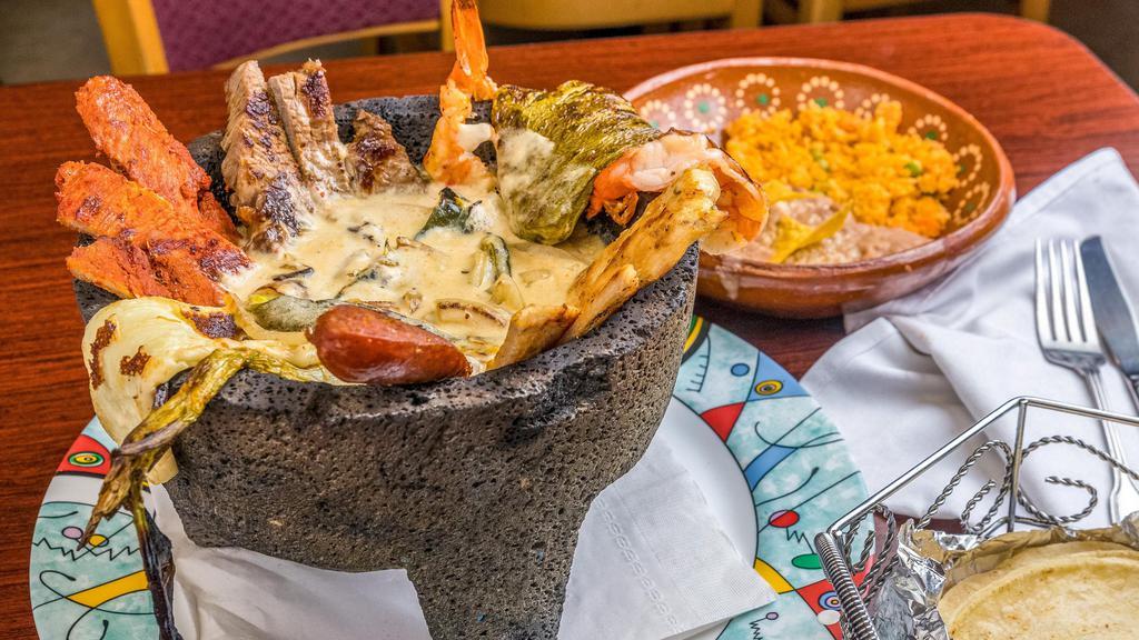 El Molcajete Special · Inside the volcanic hot stone comes with a bed of a creamy sauce with onions and chile poblano sautéed together with grilled fresh cheese, spring onions, fresh cactus (nopals), steak, chicken, shrimp, chorizo, and pork spicy meat. Served with rice, beans, and tortillas.