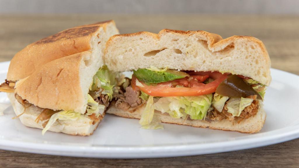 Torta Cubana · A customer favorite! Toasty, pressed telera roll filled with our house refried beans, sliced ham, spicy Mexican sausage, roasted pork loin and breaded, fried steak (milanesa). Topped with creamy avocado mayo, and fresh onions and tomatoes.