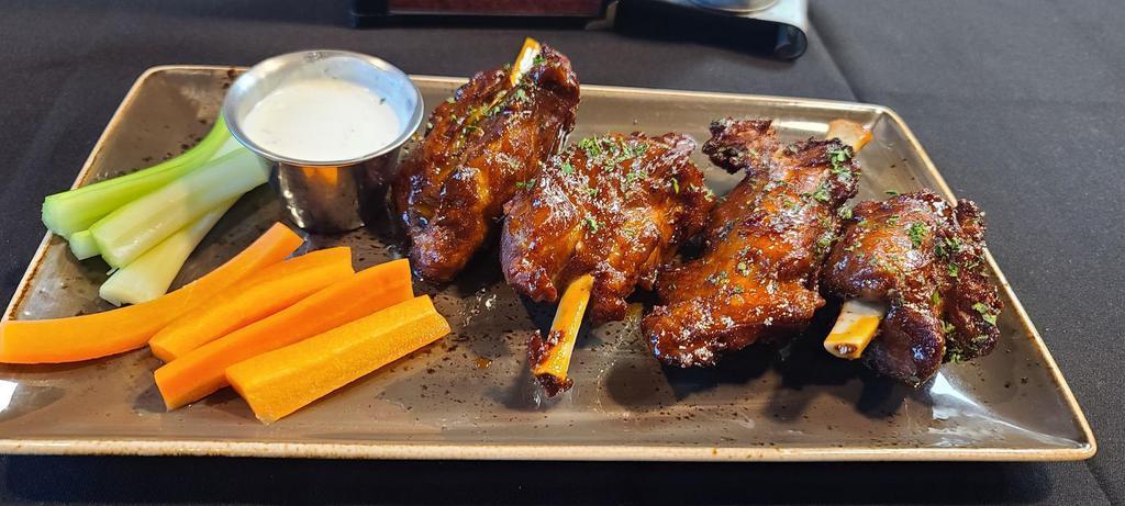 Pork Shank Wings · 4 - 4oz pork shank wings fried to crispy  perfection, tossed with a choice of buffalo sauce or Kick-In BBQ, served with bleu cheese  dressing or a spicy BBQ sauce and a side of carrots and celery