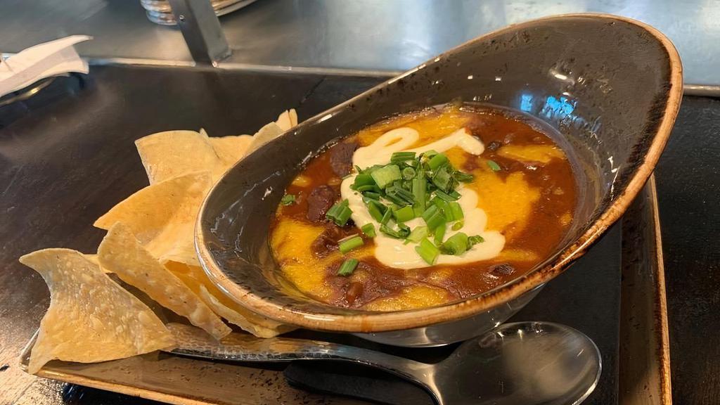 Burnt End Chili Bowl · A western style smoky chili made from burnt  ends cut from our in-house smoked brisket with fresh herbs, roasted chilies, spices, and  tomatoes in a rich beef base topped with sour cream, shredded cheddar cheese,  scallions, and a side of tortilla chips