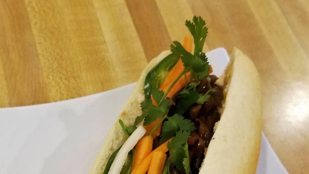 Grilled Meat Banh Mi · French baguette, cilantro, cucumber, jalapeño, pickled daikon/carrot, and spicy mayo. Protein is marinated and char-coaled grilled.