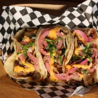 Mini Pork Tacos · Three pulled pork tacos topped with pickled red onions and giant sauce.