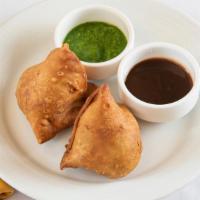 Vegetable Samosa · Two pieces. Crispy and flaky crust stuffed with potatoes, peas, and nuts.