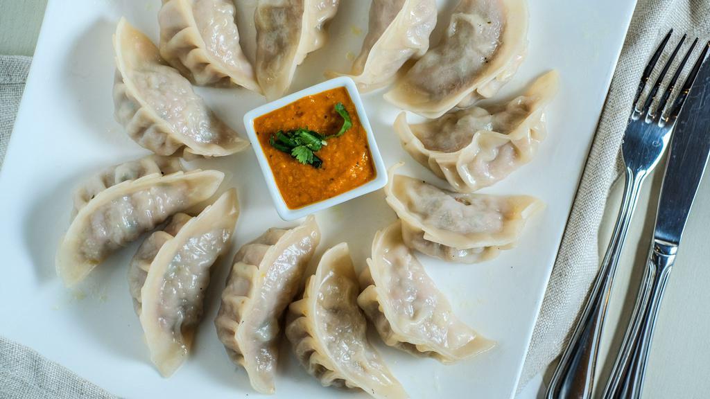 Mo Mo (6) · Steamed dumplings choice of chicken or vegetables, side of tomato.