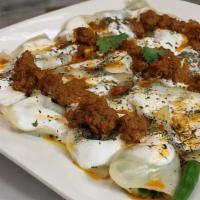 Ashak · Steamed dumplings, stuffed with scallions, topped with yogurt, seasoning, and meat sauce.