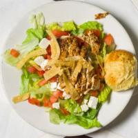 Jamaican Jerk Chicken Salad · Fresh greens, tomato and crumbled feta topped with spicy grilled jerk chicken and crisp tort...