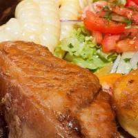 Lechon Al Horno · roasted pig served with baked potato, plantain, sweet potato, corn and salad