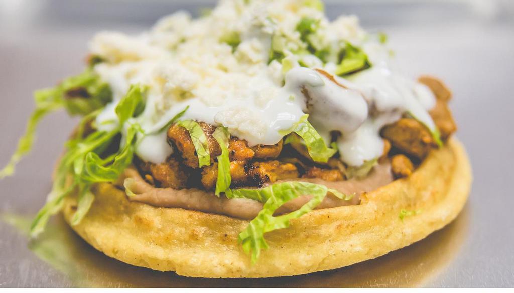 Chorizo Sope · Pork sausage. A handmade tortilla fried and topped with beans, lettuce, queso fresco, and crema.