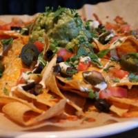Nachos · Crunchy chips layered with pepperjack and cheddar cheese, roasted garlic, tomatoes, jalapeno...